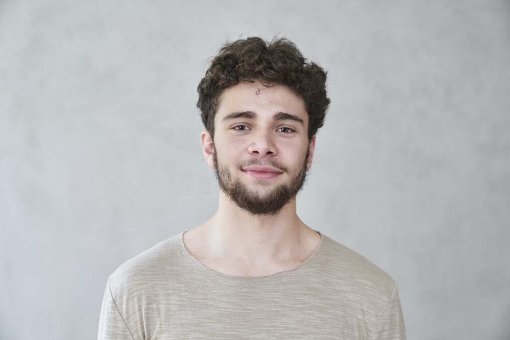 Portrait of smiling young man in front of grey wall